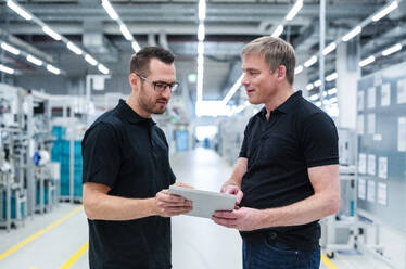 Zwei Kollegen teilen sich ein digitales Tablet in einer Fabrik - DIGF20862