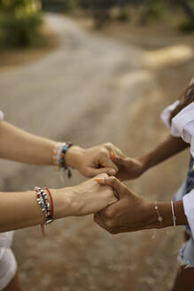 Teenage girl holding hands of mother in forest - ANNF00499