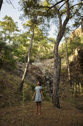 Teenager-Mädchen steht in der Nähe von Bäumen im Wald - ANNF00537