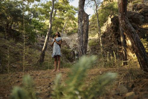 Teenager-Mädchen mit verschränkten Händen im Wald stehend - ANNF00539