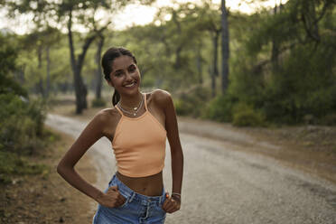 Happy teenage girl with hands in pockets at sunset - ANNF00559