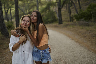 Verspieltes Mädchen im Teenageralter umarmt Mutter im Wald - ANNF00575