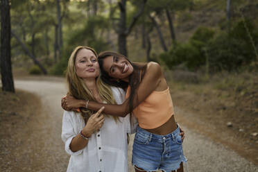 Smiling teenage girl hugging mother in forest - ANNF00576