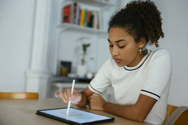 Student beim Lernen und Schreiben auf einem Tablet-PC am Schreibtisch - EBSF03915