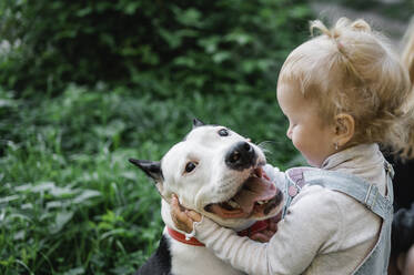 Blondes Mädchen umarmt Hund im Park - ANAF02184