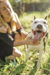 Frau mit Hund, der im Park die Zunge herausstreckt - ANAF02192