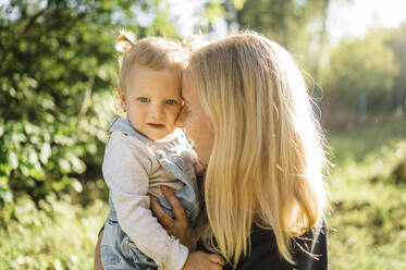 Happy mother embracing daughter in park - ANAF02196