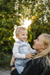Lächelnde blonde Frau mit Tochter im Park - ANAF02200