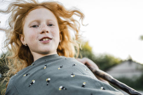 Glückliches rothaariges Mädchen schwingt im Park - ANAF02207