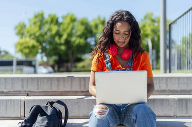 Junge Studentin benutzt Laptop auf den Stufen des Campus - PGF01715