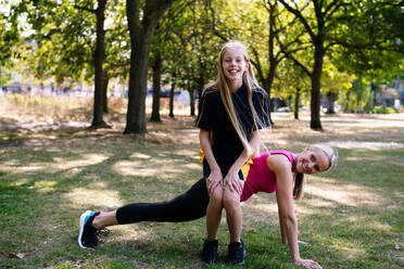 Smiling mother and daughter exercising in park - AMWF01879