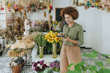 Lächelnde Floristin mit Tablet-PC im Blumenladen - YTF01183