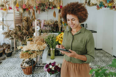 Lächelnde Floristin mit Tablet-PC im Blumenladen - YTF01184