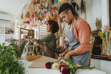 Young florists making flower bouquet at desk in shop - YTF01222