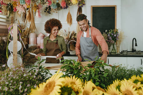 Lächelnde Ladenbesitzer machen Blumenstrauß am Schreibtisch - YTF01225