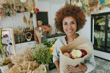 Lächelnder Kunde mit Blumenstrauß im Geschäft - YTF01232