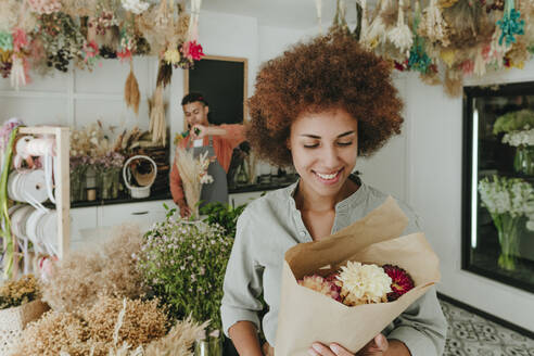 Smiling customer looking at flowers in bouquet - YTF01233