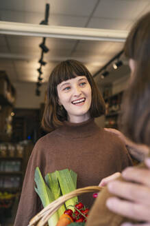 Lächelnde Frau in braunem Hemd vor einem Supermarkt - AMWF01895