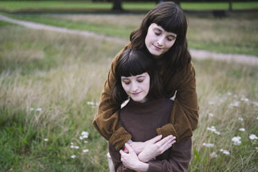 Loving twin sisters hugging at park - AMWF01910