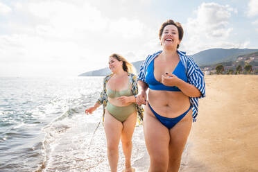 Group of beautiful plus size women with swimwear bonding and having fun at the beach - Group of curvy female friends enjoying summertime at the sea, concepts about body acceptance, body positive and self confidence - DMDF06969
