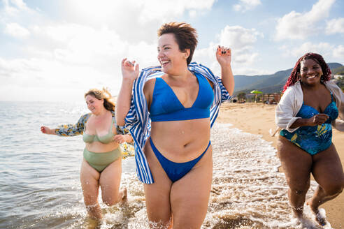 Group of beautiful plus size women with swimwear bonding and having fun at the beach - Group of curvy female friends enjoying summertime at the sea, concepts about body acceptance, body positive and self confidence - DMDF06970