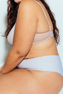 Plus size woman posing in studio in lingerie. Model on white