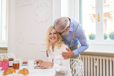 Happy senior couple having breakfast at home - Married couple on the 60's in their apartment, concepts about senority and relationship - DMDF07053