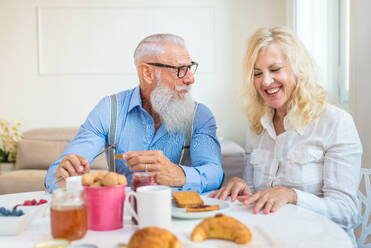 Glückliches älteres Ehepaar beim Frühstück zu Hause - Ehepaar in den 60er Jahren in ihrer Wohnung, Konzepte über Senorität und Beziehung - DMDF07058
