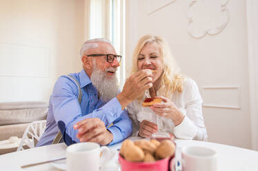 Glückliches älteres Ehepaar beim Frühstück zu Hause - Ehepaar in den 60er Jahren in ihrer Wohnung, Konzepte über Senorität und Beziehung - DMDF07059
