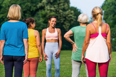 Multiethnische Gruppe älterer Frauen beim Training im Park mit einem Fitnesstrainer - Aktive ältere Menschen beim Sport in der Natur - DMDF07093