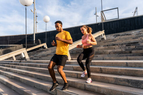 Interracial Sportlerpaar trainiert im Freien - Multikulturelles Paar trägt Sportbekleidung und absolviert ein funktionelles Training im Freien, um Körper- und Bauchmuskeln, Ausdauer und Herz-Kreislauf-System zu stärken - DMDF07113