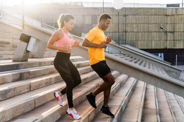 Fit and diverse couple working out outdoors - Multicultural duo in athletic gear engaging in functional training to enhance strength, endurance, and core muscles - DMDF07114