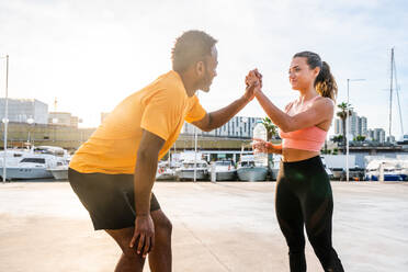 Fit and diverse couple working out together outdoors, building strength, endurance, and core muscles through functional exercises - DMDF07118