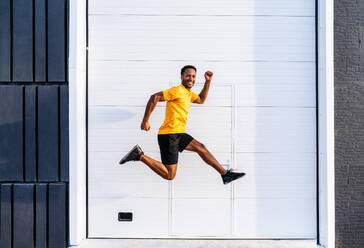 Schwarzer hispanischer Sportler, der in der Stadt im Freien trainiert - Afrikanischer Mann mit festem, muskulösem Körper, der ein funktionelles Training durchführt, um das Herz-Kreislauf-System, die Körpermuskeln und die Bauchmuskeln zu trainieren - DMDF07119