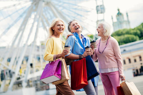 Schöne glückliche ältere Frauen, die sich im Freien treffen und im Stadtzentrum einkaufen gehen - Hübsche und fröhliche alte weibliche Erwachsene, die sich im Freien treffen und Spaß haben - DMDF07146