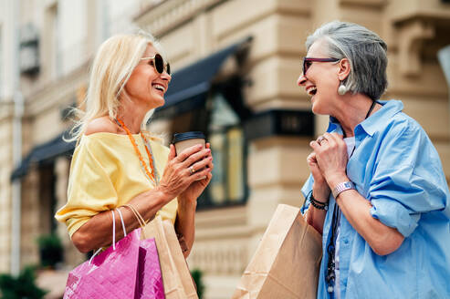 Schöne glückliche ältere Frauen, die sich im Freien treffen und im Stadtzentrum einkaufen gehen - Hübsche und fröhliche alte weibliche Erwachsene, die sich im Freien treffen und Spaß haben - DMDF07151