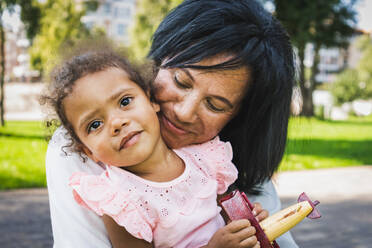 Schöne glückliche afroamerikanische Familie im Park - Schwarze Familie hat Spaß im Freien, Oma kuschelt mit ihrer kleinen Enkelin - DMDF07176