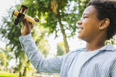 Schöne glückliche afrikanische amerikanische Familie im Park - Schwarze Familie hat Spaß im Freien, niedlicher kleiner Junge spielt mit Flugzeug Spielzeug - DMDF07178