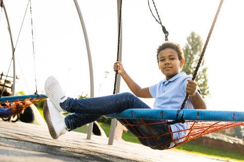 Schöne glückliche afroamerikanische Familie im Park - Schwarze Familie hat Spaß im Freien, süßer Junge spielt auf der Schaukel - DMDF07205