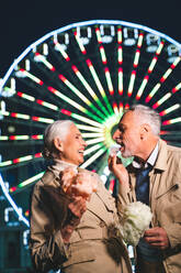 Beautiful senior couple dating outdoors - Mature couple having fun at amusement park, concepts about elderly and lifestyle - DMDF07269