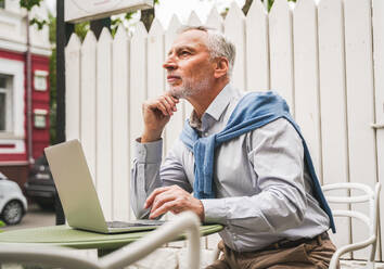 Cheerful senior man portrait - Mature adult using his computer laptop in a bar coffeehouse, concepts about lifestyle, senior people, technology and smart working - DMDF07298