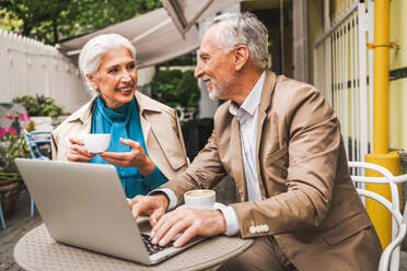 Schönes älteres Paar, das sich im Freien verabredet - Älteres Paar mit Laptop, das in einem Bar-Restaurant sitzt, Konzepte über ältere Menschen, Lebensstil und Technologie - DMDF07302