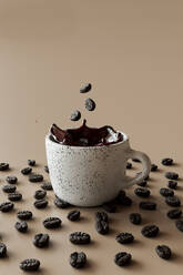 3D-Rendering von Kaffeebohnen, die in eine Tasse Kaffee fallen - GCAF00432