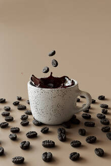 3D-Rendering von Kaffeebohnen, die in eine Tasse Kaffee fallen - GCAF00432