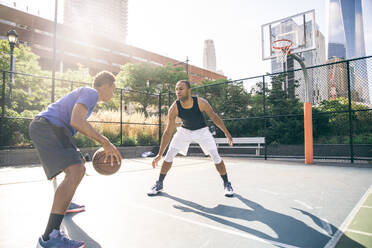 Zwei afroamerikanische Athleten spielen Basketball im Freien - Basketballer trainieren auf einem Platz in New York - DMDF07342