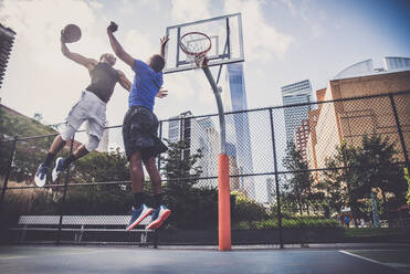 Zwei afroamerikanische Athleten spielen Basketball im Freien - Basketballer trainieren auf einem Platz in New York - DMDF07344