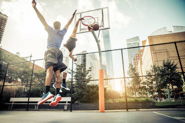 Zwei afroamerikanische Athleten spielen Basketball im Freien - Basketballer trainieren auf einem Platz in New York - DMDF07345
