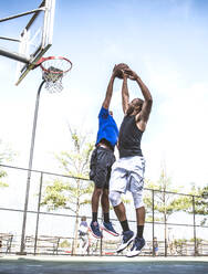 Zwei afroamerikanische Athleten spielen Basketball im Freien - Basketballer trainieren auf einem Platz in New York - DMDF07346