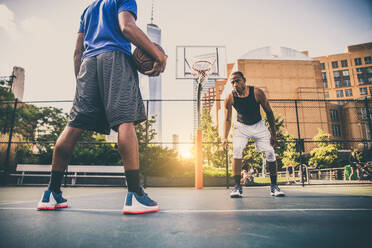 Zwei afroamerikanische Athleten spielen Basketball im Freien - Basketballer trainieren auf einem Platz in New York - DMDF07347