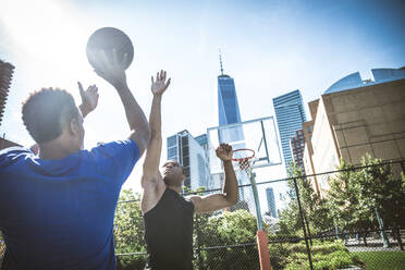 Zwei afroamerikanische Athleten spielen Basketball im Freien - Basketballer trainieren auf einem Platz in New York - DMDF07351